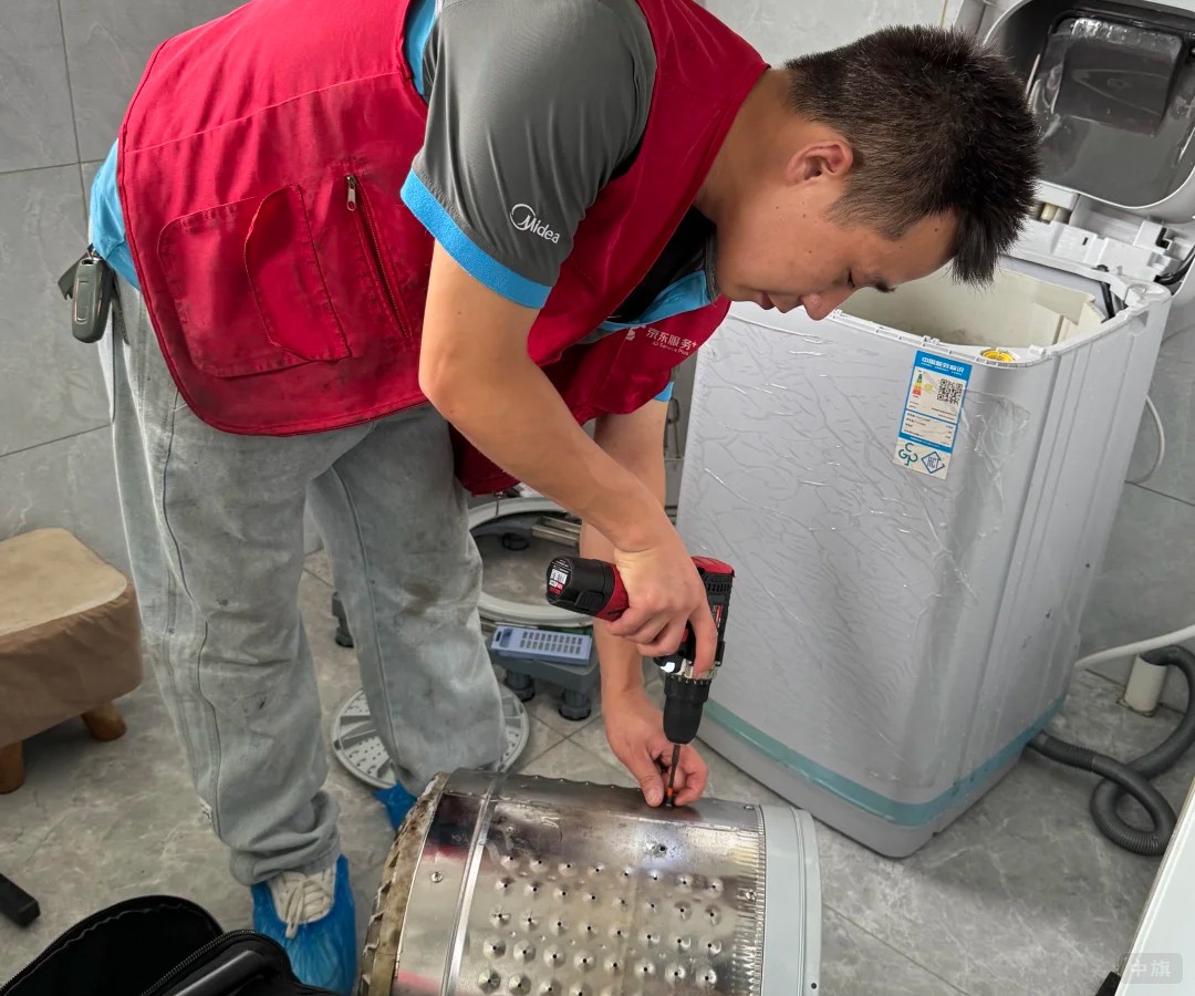 師傅在用電動扳手拆洗衣機的滾筒